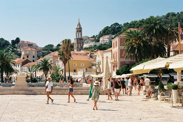 Turisti passeggiano in una piazza di una cittadina di mare